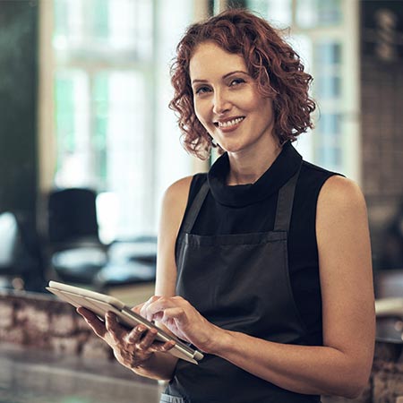 Hairdresser smiling whilst using an iPad